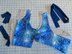 Individual, unsewn pattern pieces cut from beige swim lining and blue firework swim fabric.